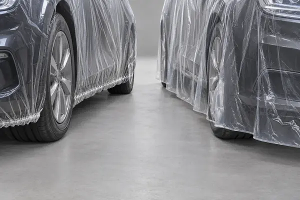 Close view of transparent disposable car cover lower edges showing elastic gathering and an open draped edge
