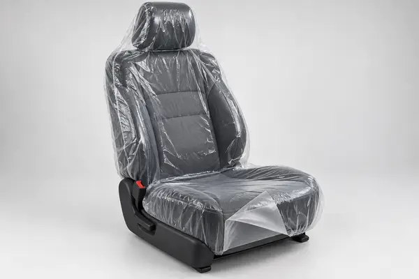 Clear disposable automotive seat cover with a folded edge showing smooth and textured film layers