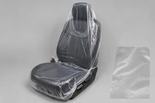 Transparent embossed disposable plastic cover fitted over an automotive front seat with a film texture sample