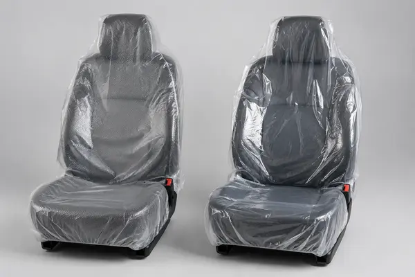 Embossed and smooth transparent disposable plastic covers fitted to two automotive front seats